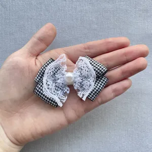 Close-up of handmade plaid bow hair clip with lace edge and pearl in hand for size
