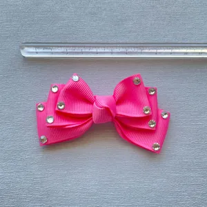 Detail view of pink bow hair clip with rhinestones and 9cm measurement ruler