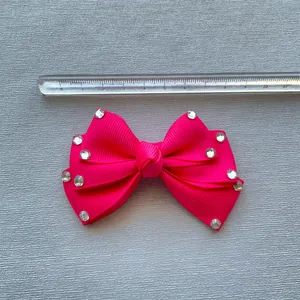 Detail view of 8cm rose pink ribbon bow with rhinestones next to a measuring ruler