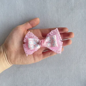 Gros plan d'un nœud papillon en dentelle rose avec motif floral tenu par une main