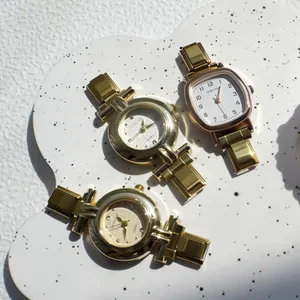 Dettaglio di orologi al quarzo dorati su vassoio bianco con quadranti tondi e rettangolari