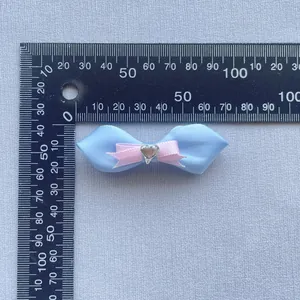 Detailansicht einer 50mm Strass-Schleife mit blauen Bändern und Herz-Edelstein-Dekor