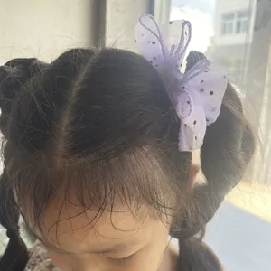 Close-up of a purple mesh bow hair clip with black polka dots on a girl's hair