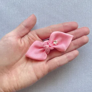 Pink ribbed grosgrain bow accessory with star rhinestone held in hand for scale