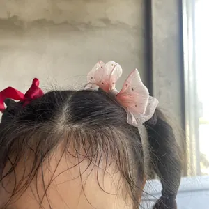 Detail of red satin and pink tulle bow hair clips worn on a young girl ponytail
