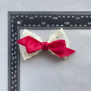 Detail einer roten Satinschleife mit weißer Spitze und Blumenstickerei, 95 mm breit