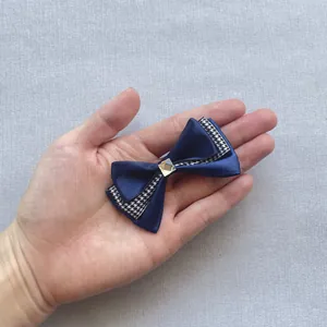 Detail of dark blue satin bow hair clip with houndstooth edge and square rhinestone