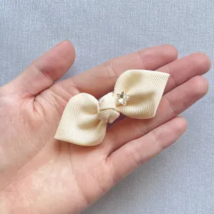 Detail of beige grosgrain ribbon bow with a star-shaped crystal held in hand