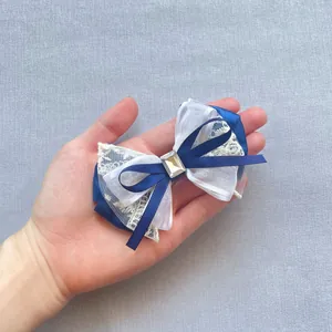 Close-up of navy blue ribbon and white lace bow with center crystal for DIY hair clips