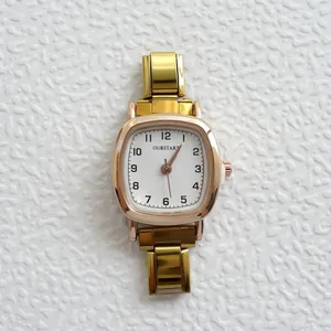 Dettaglio di un orologio al quarzo quadrato dorato con quadrante bianco e cinturino in metallo