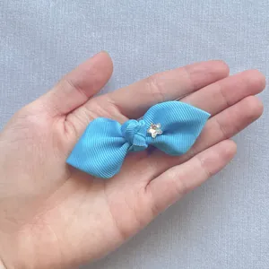 Blue grosgrain ribbon bow with star rhinestone on hand showing the actual size