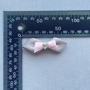 Detaillierte Draufsicht einer handgefertigten grauen und rosa Schleife mit Kristallherz