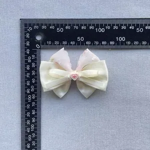 Floral print bow hair accessory with pink heart center and multi-layered ribbon design