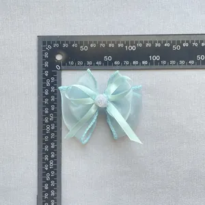 Detailansicht der hellblauen Organza Schleife mit kleiner Rose und Lineal zur Messung