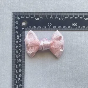 Dettaglio del fiocco in pizzo rosa e paillettes con misura della scala di 60 mm