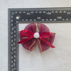 Detailansicht einer burgunderroten Organza-Schleife mit weißer Rosenperle und Maßstab