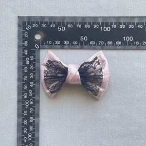 Dettaglio fiocco rosa glitterato con pizzo nero e righello per misurazione delle dimensioni