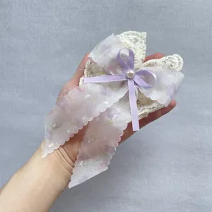 Détail d'un nœud en organza floral lavande avec dentelle blanche et fausse perle