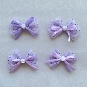 Détail de nœuds en tulle lavande à pois avec décoration centrale de perle rose blanche