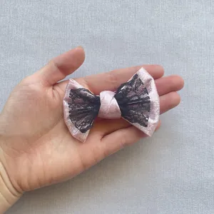 Dettaglio del tessuto glitterato rosa e pizzo nero sull'elastico per capelli a doppio fiocco