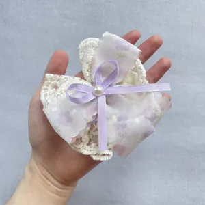 Détail d'une pince à cheveux en dentelle blanche et fleurs violettes avec perle centrale