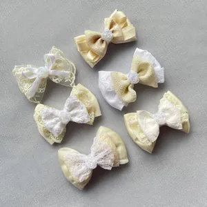 Detail of six cream fabric bows with resin rose centers for DIY crafts and accessories