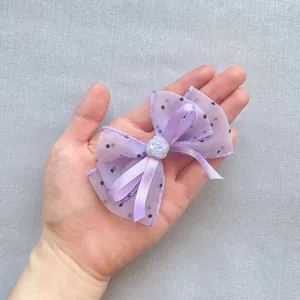 Nœud à cheveux violet à pois en tulle avec rose nacrée blanche tenu à la main