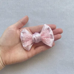 Dettaglio del fiocco rosa glitterato con pizzo tenuto in mano per la misura