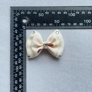Macro detail of a 60mm beige handmade bow accessory with sparkling heart rhinestone and gems