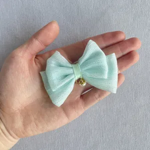 Detail of mint green mesh bow with silver glitter and pearl charm held in hand