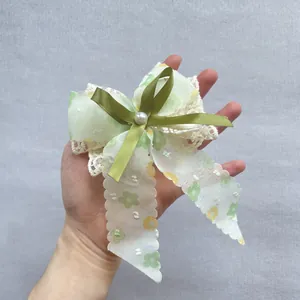 Détail du nœud à cheveux floral avec dentelle, ruban vert et perle décorative