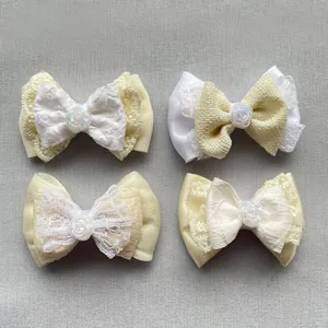Macro shot of cream DIY fabric bows with lace, satin textures and pearl rose accents