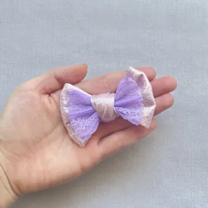 Dettaglio dell'elegante fiocco per capelli in pizzo a doppio strato color lavanda e rosa