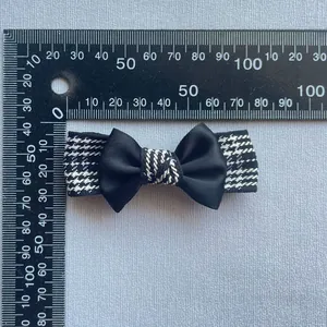 Detailed size measurement of handmade black silk and houndstooth bow hair clip with a ruler