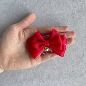 Detail of red satin bow hair clip with silver studs and white faux pearl drop decoration