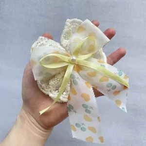 Détail d'un nœud fait main avec ruban jaune, dentelle et perle blanche au centre