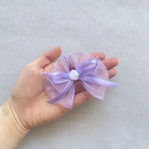 Detail einer lila doppellagigen Organza-Schleifen-Haarklammer mit weißer Kunstharz-Rose