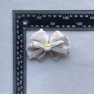 Detailed view of floral lace bow with strawberry resin accessory and scale measurement