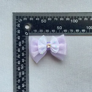 Macro detail of purple mesh bow accessory with sequins and star charm on grey fabric
