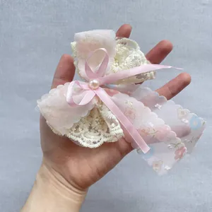 Détail du nœud de cheveux en organza rose fleuri avec dentelle, perles et rubans