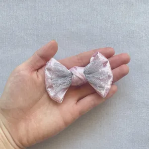 Dettaglio di fiocco rosa glitterato con pizzo grigio mostrato per evidenziare le dimensioni