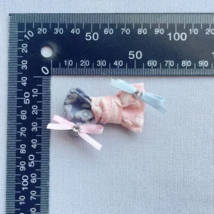 Dettaglio di fiocco in tessuto fatto a mano con pois e strass accanto a un righello