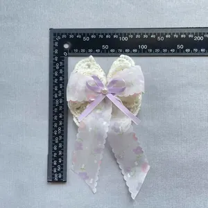 Détail d'accessoire cheveux nœud en dentelle, ruban lavande, perle et motif floral, 15cm