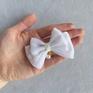 Detail of white mesh bow with silver glitter and a pearl charm held in hand