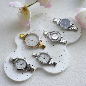 Dettaglio collezione orologi al quarzo in oro rosa e argento su espositore bianco
