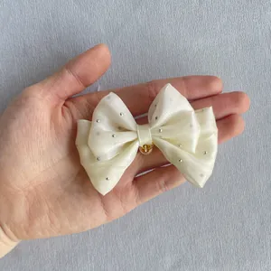 Macro shot of ivory organza bow with silver rhinestones and central gold bead detail