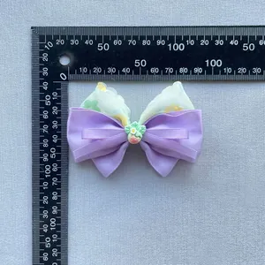 Close-up of floral print bow accessory with strawberry center being measured for size