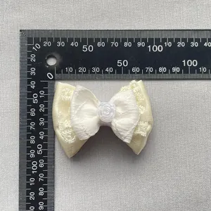 Detail of a 6cm beige ribbon bow with lace layers and a resin rose flower center