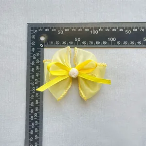 Makroaufnahme einer gelben Organza-Schleife mit Rose und 9,5 cm Maßstab auf dem Lineal