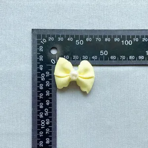 Detailed view of a light yellow ribbon bow with pearl bead and measurement scale